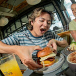 Boy eating a burger at Miss Lucy Bar at Lylo Hostel Auckland